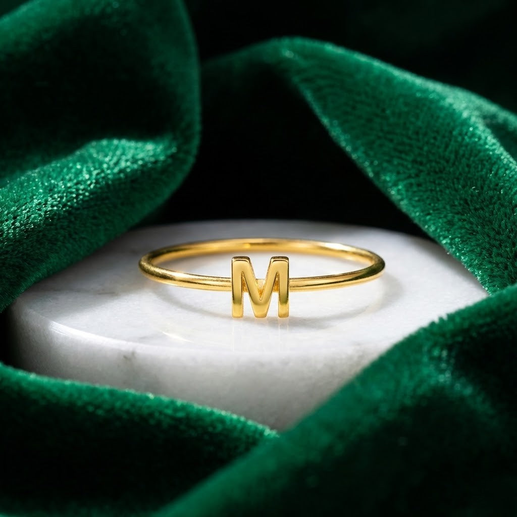 Personalized initial ring, thin gold-tone band with a letter, letter 'M' on a marble disc with green velvet