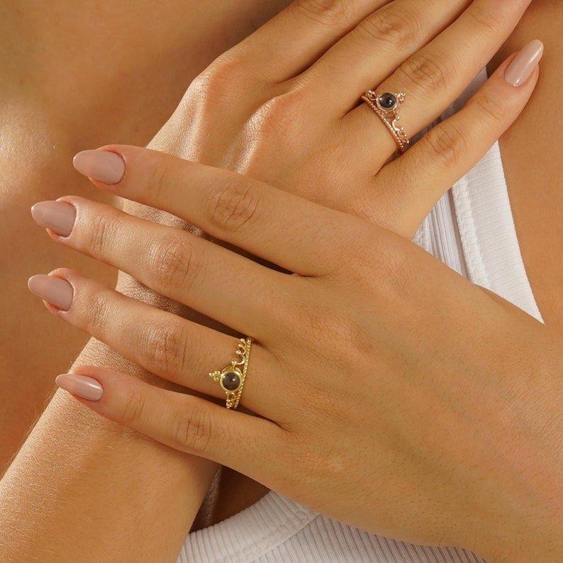 Crown projection ring with a hidden photo in the round stone, gold-tone crown band, worn on a hand
