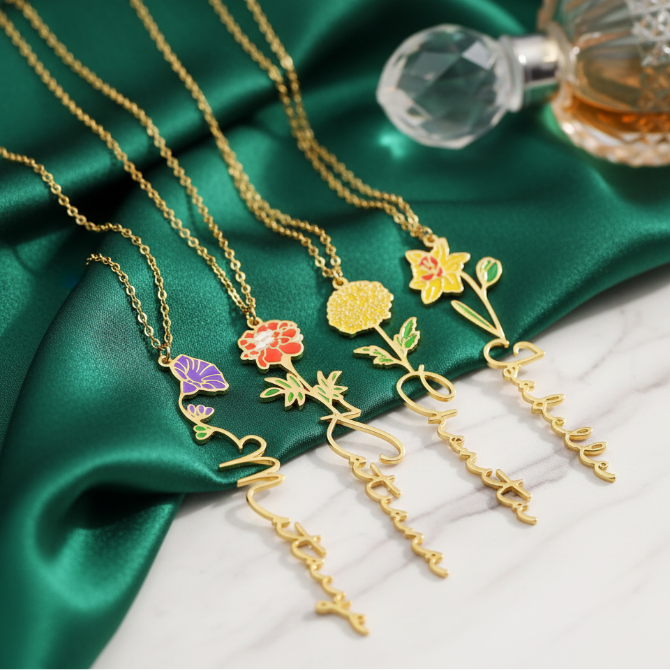 Birth flower name necklace: coloured birth flower with a name below, gold-tone, four necklaces on green satin with a perfume bottle