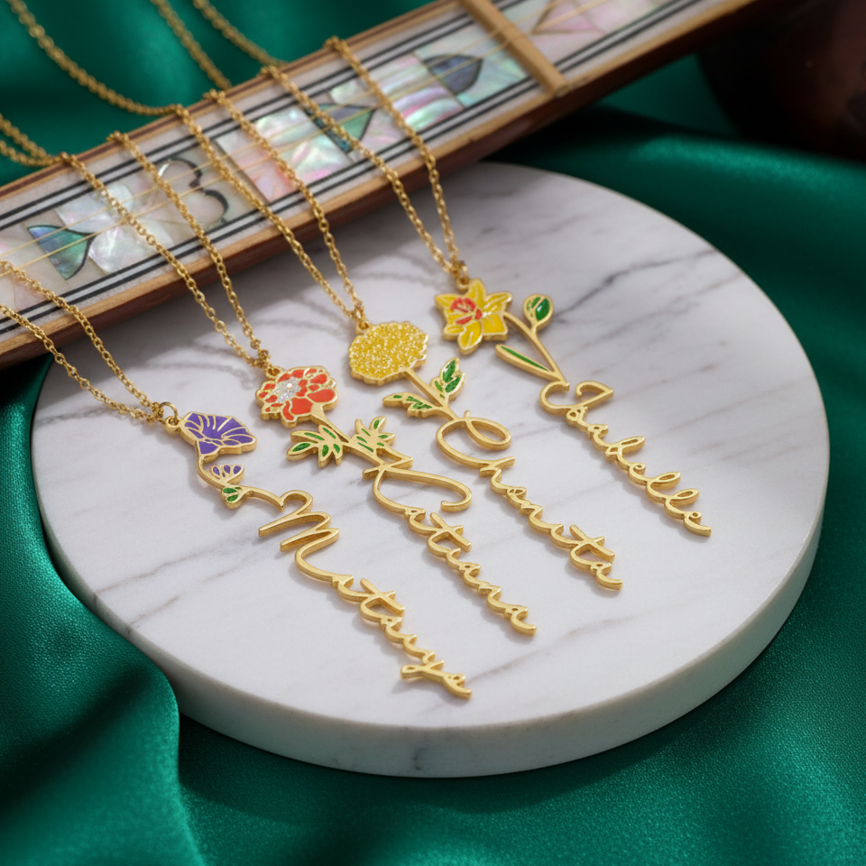 Birth flower name necklace: coloured birth flower with a name below, gold-tone, four necklaces on a marble disc