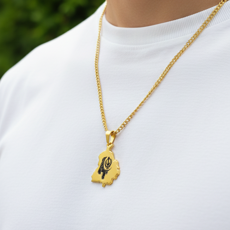Gold-plated Punjab map pendant with a black Khanda design on a curb chain, worn over a white tee