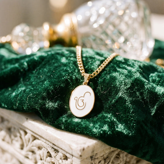 Ik Onkar enamel pendant on green velvet beside a crystal bottle