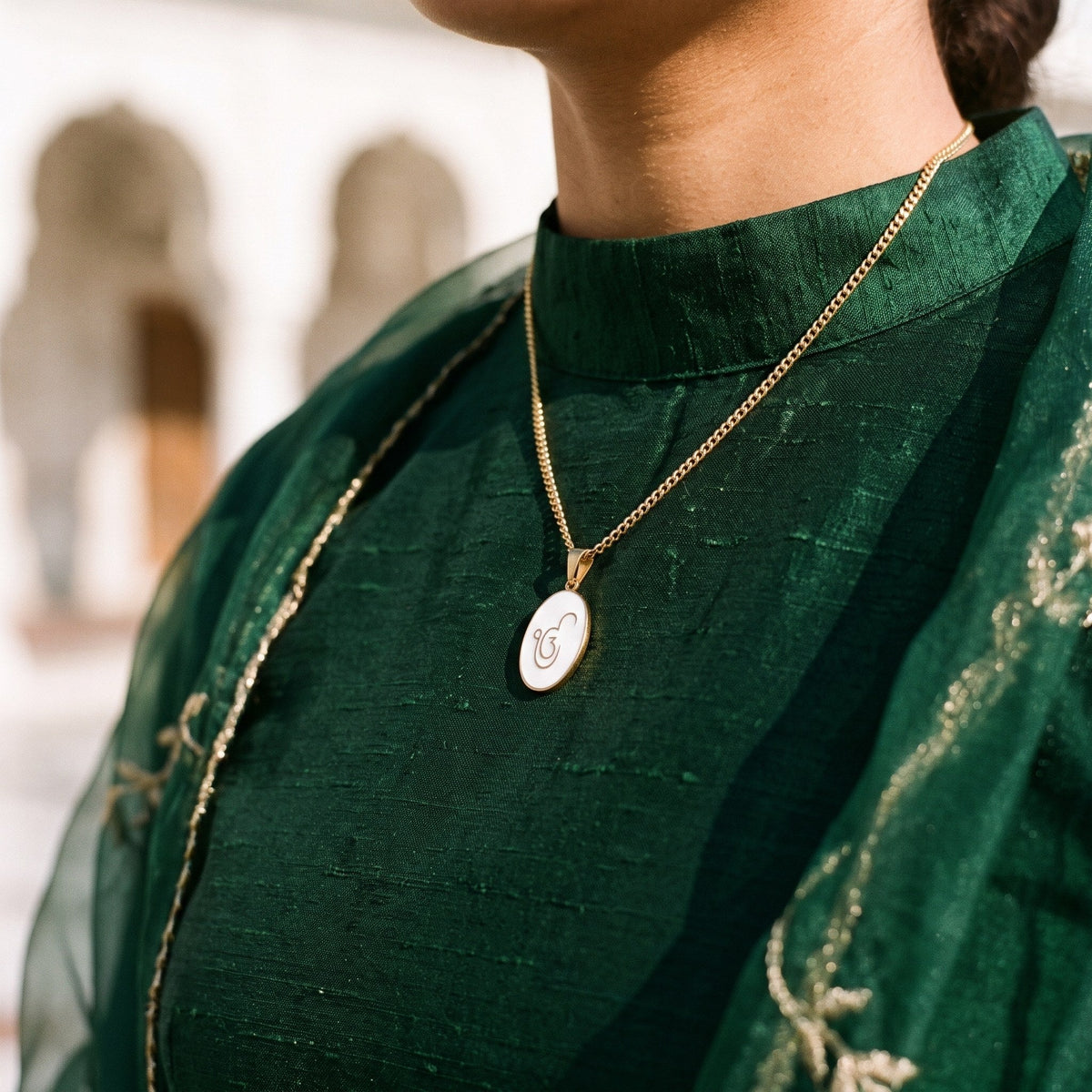 Ik Onkar enamel pendant necklace worn with a green suit