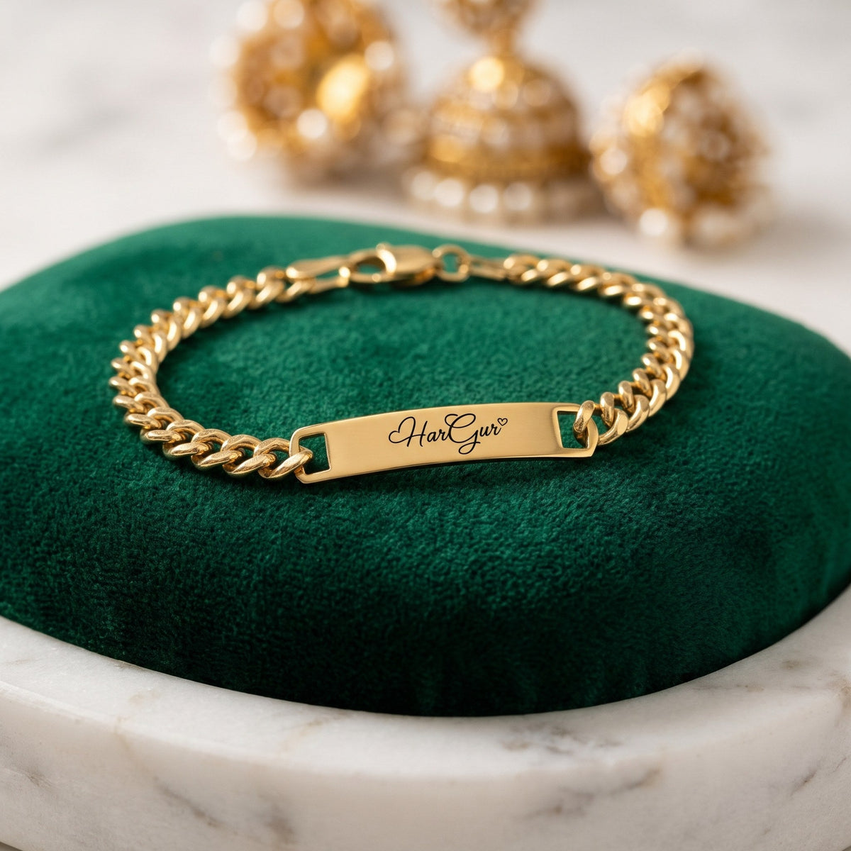 Gold name ID bracelet with HarGur closed on a green velvet cushion