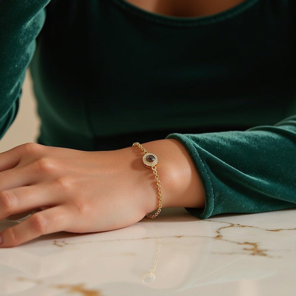 Round stone projection bracelet with a hidden photo, thin chain and sparkling stones around the round stone, worn on a wrist with a green sleeve
