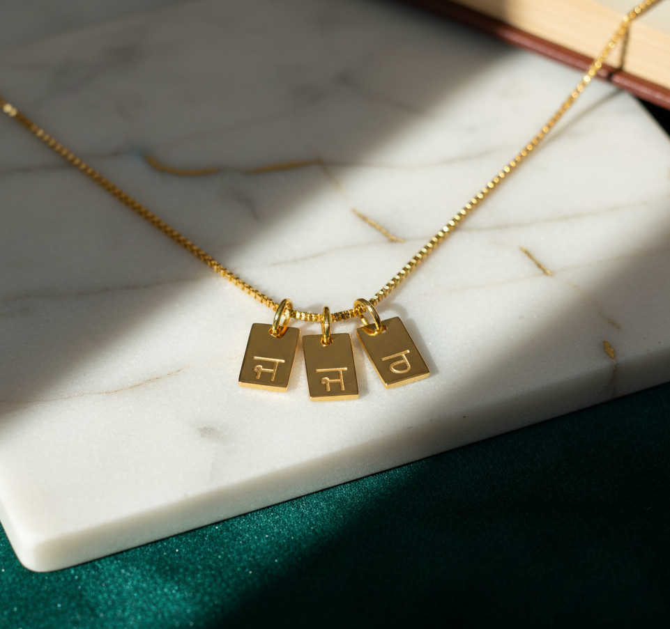 Gold necklace with three rectangular pendants on a marble surface