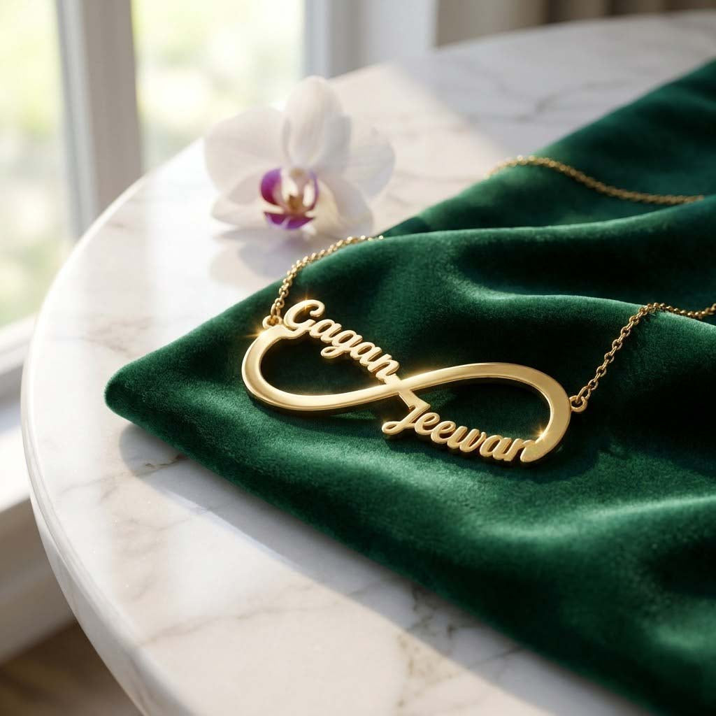 Gold-plated infinity name necklace with two names 'Gagan' and 'Jeewan', on green velvet with an orchid