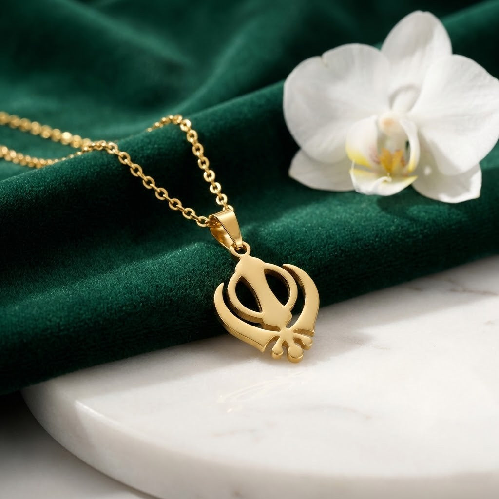 Gold-plated Khanda pendant necklace, on green velvet with a white orchid