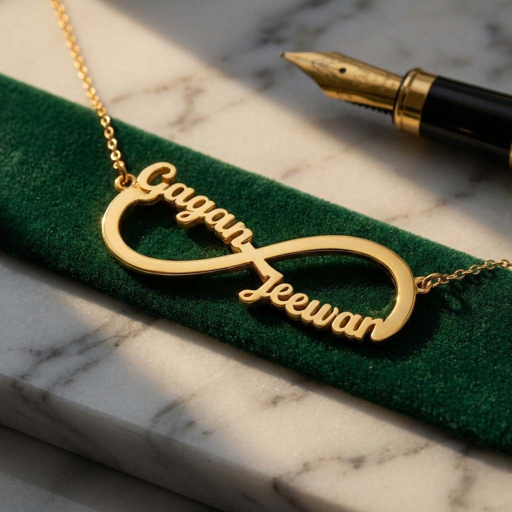Gold-plated infinity name necklace with two names 'Gagan' and 'Jeewan', close-up on velvet with a pen