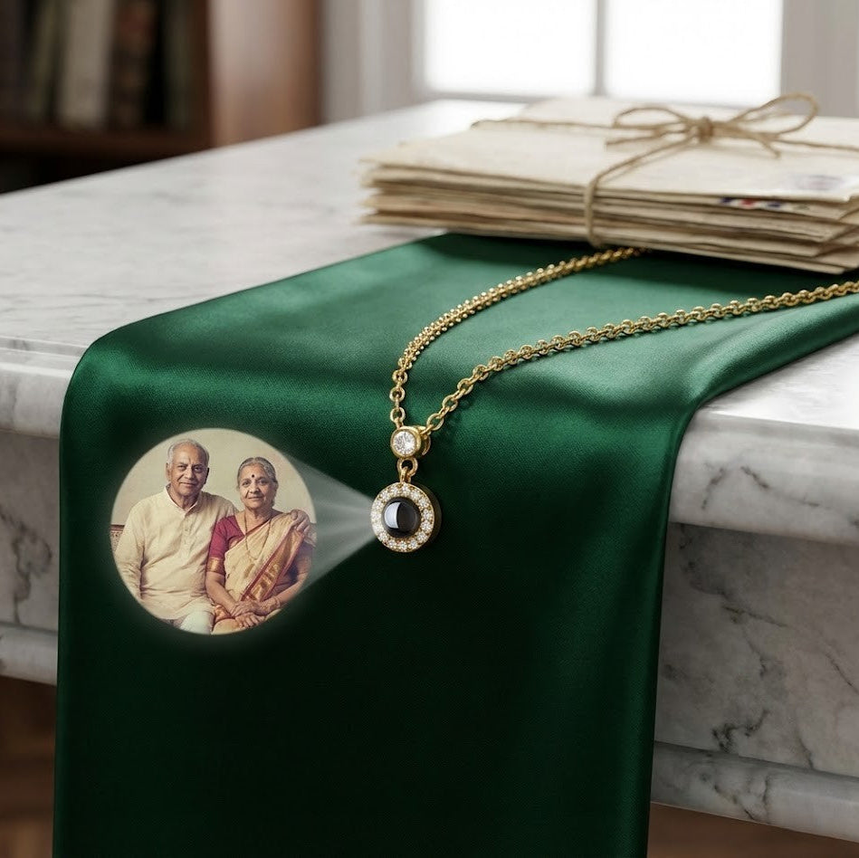 Single stone round projection pendant with a hidden photo, small sparkling stones above the round stone, on green satin, with the projected photo of an elderly couple shown beside it