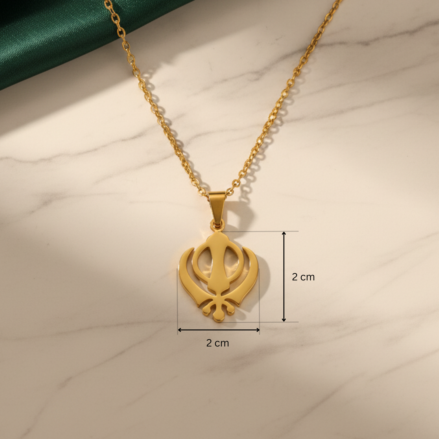 Gold necklace with a pendant on a marble surface, showing measurements.
