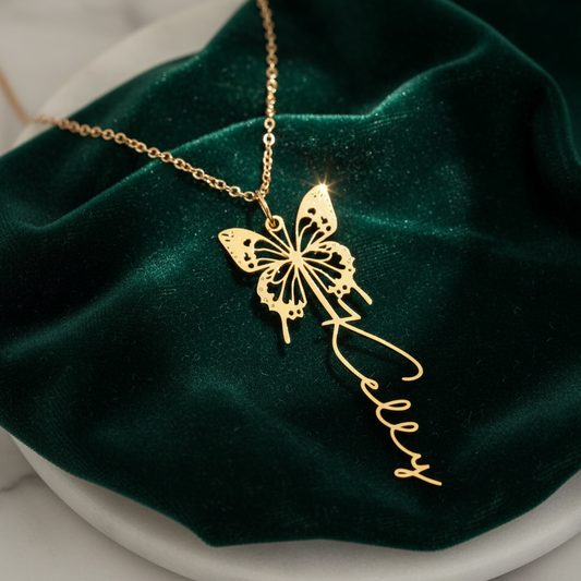 Gold butterfly necklace with 'Kelly' on a green velvet background