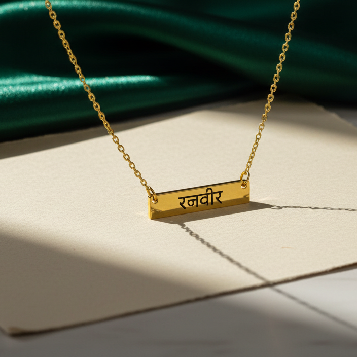 Gold necklace with a pendant on a white surface with green fabric in the background