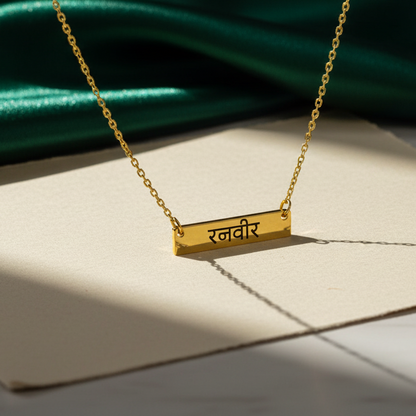 Gold necklace with a pendant on a white surface with green fabric in the background