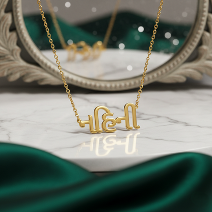 Gujrati_name_necklace Gold necklace with a name pendant on a decorative stand with a green fabric background