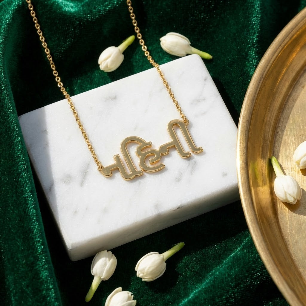 Gold necklace with a unique design on a marble surface with tulips, on a green fabric background. Gujrati_name_necklace