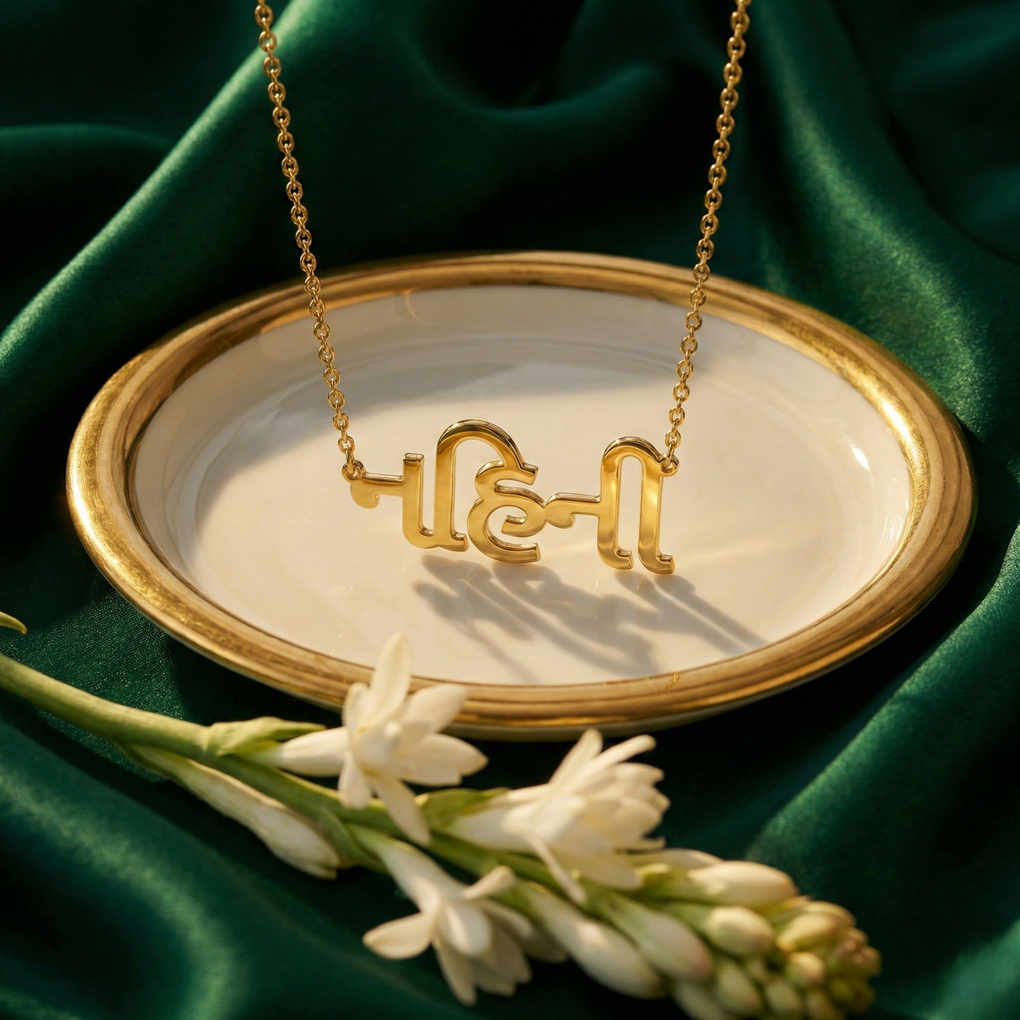 Gujrati_name_necklace Gold necklace with Hebrew letters on a white dish against a green fabric background