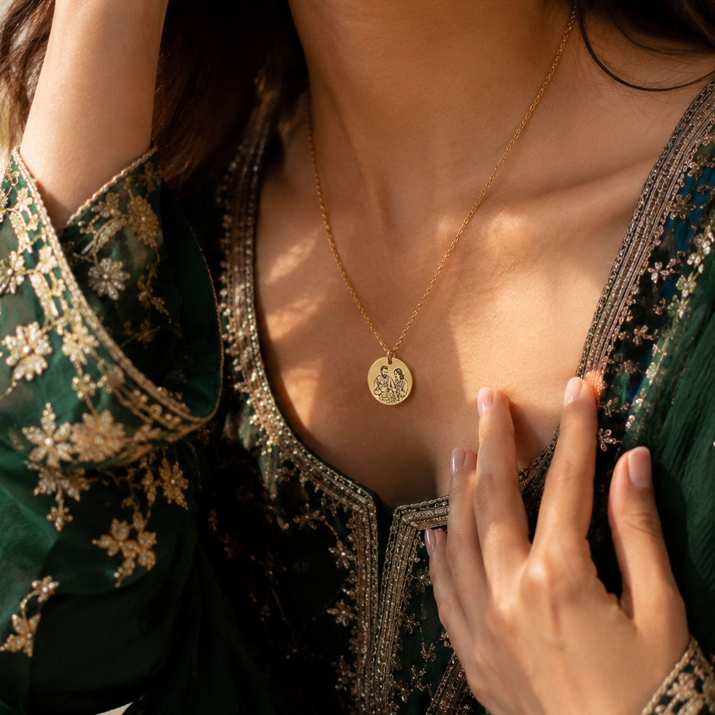 Woman wearing a green embroidered outfit with a gold necklace and ring.