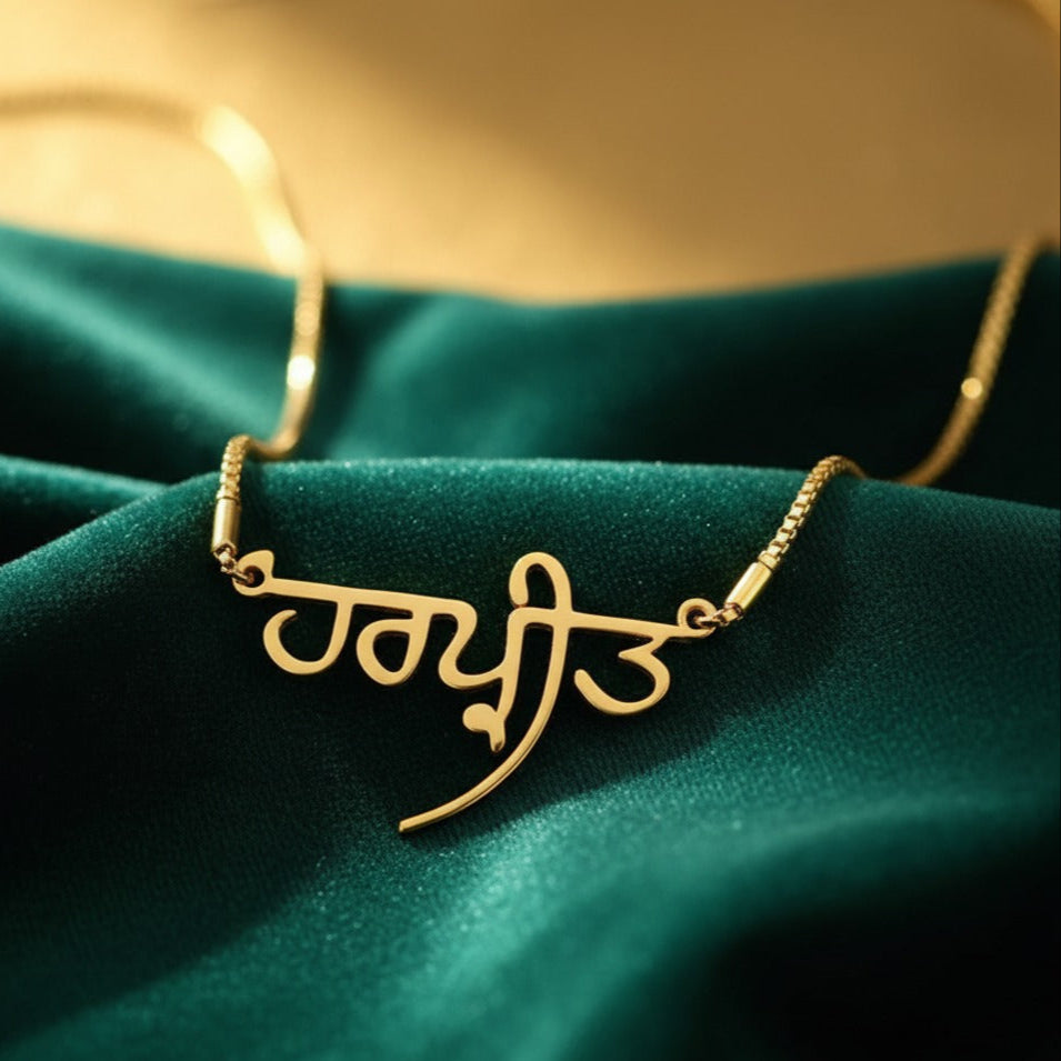 Punjabi Gold necklace with a name pendant on a green fabric background