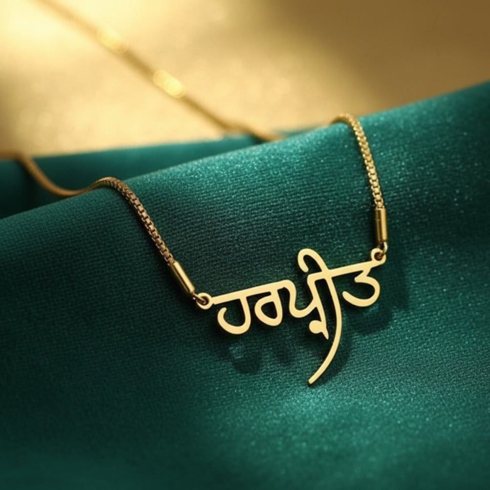 Gold necklace with a script design on a green fabric background