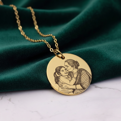 Gold necklace with a pendant featuring an engraved design on a green fabric background