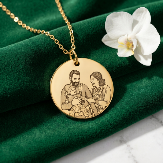 Gold necklace with a round pendant featuring an engraving of a family on a green fabric background.