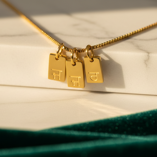 Gold necklace with three rectangular pendants on a marble surface