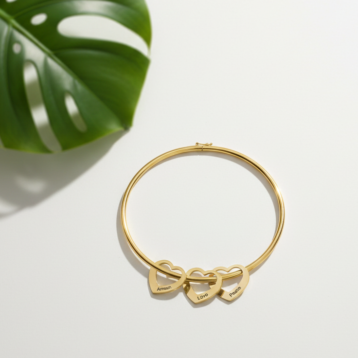 Gold bracelet with bow design on a light surface with a green leaf