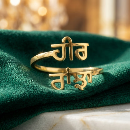 Gold double name ring with Punjabi names Heer and Ranjha on green velvet
