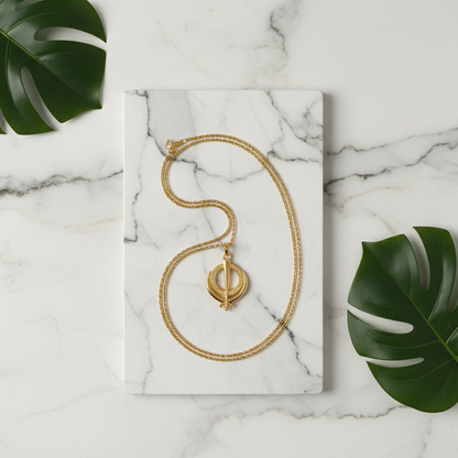 Gold necklace on a marble surface with green leaves