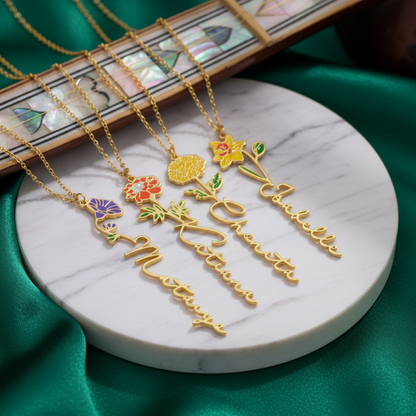 Gold necklaces with floral and script pendants on a marble surface.