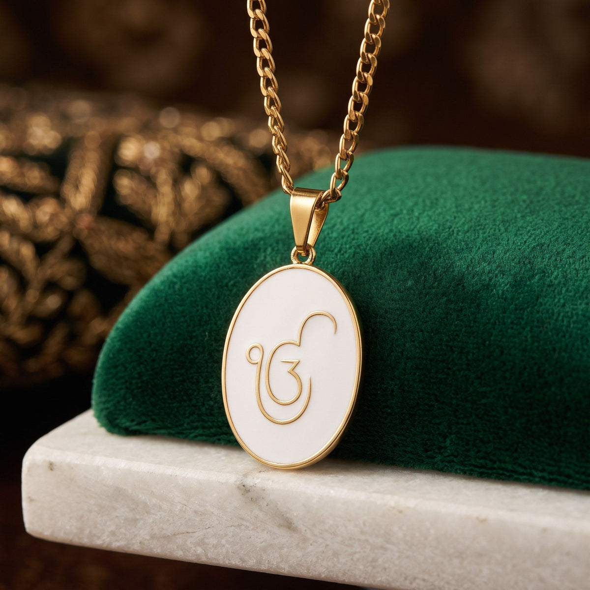Ik Onkar pendant in gold on white enamel, on a green velvet cushion