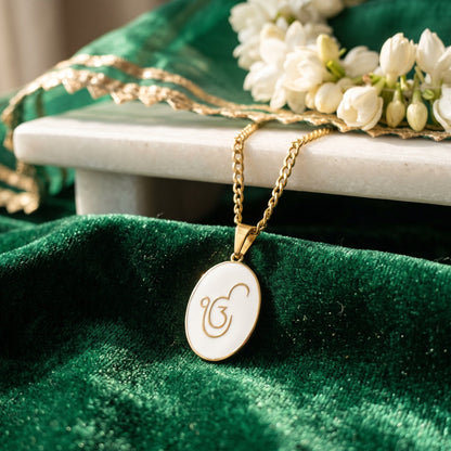 Ik Onkar enamel pendant on green velvet below a marble shelf with jasmine
