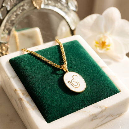 Ik Onkar enamel pendant on green velvet in a marble tray, an orchid behind