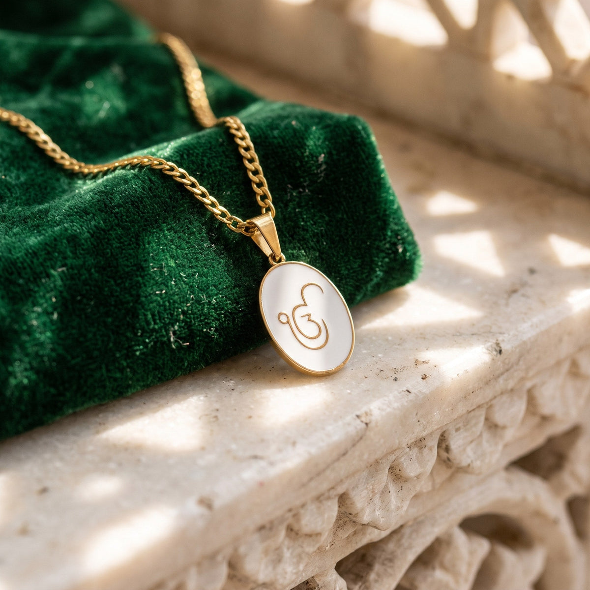 Ik Onkar enamel pendant on green velvet and carved marble