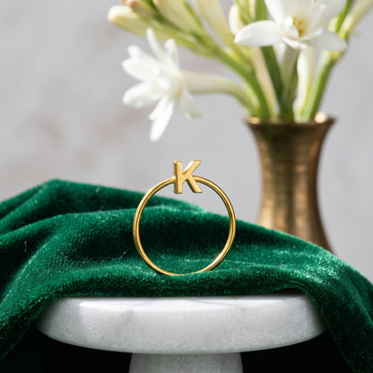 Thin gold initial ring with letter K on green velvet