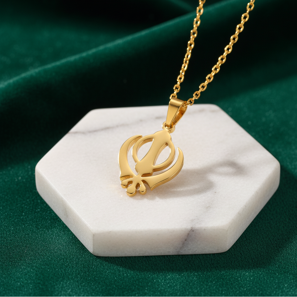 Gold necklace with a pendant on a white marble stand against a green background