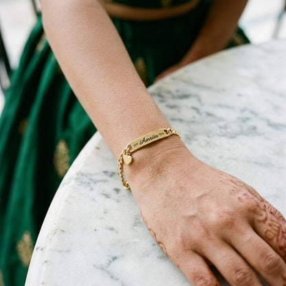 Gold heart charm name bracelet on a woman's wrist
