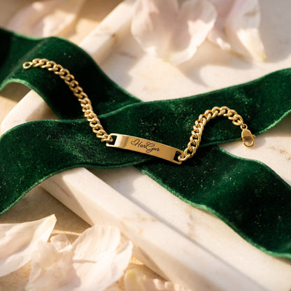 Gold name ID bracelet with HarGur across a green velvet ribbon on marble