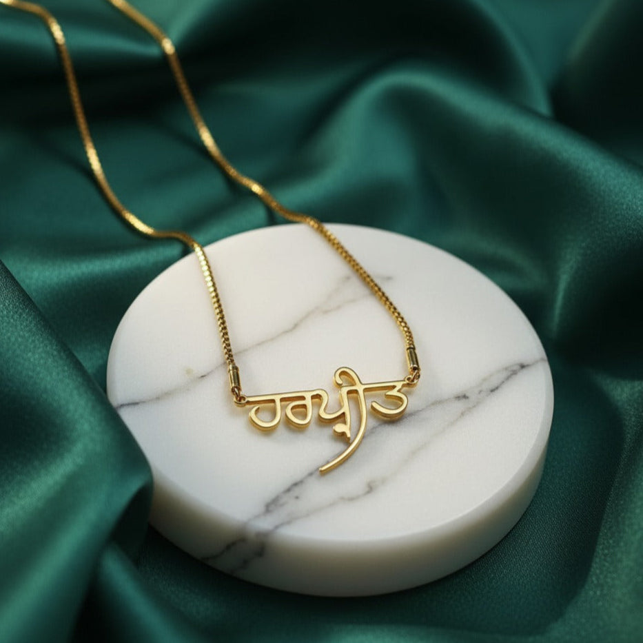 Punjabi Gold necklace with a unique design on a marble coaster with a green satin background